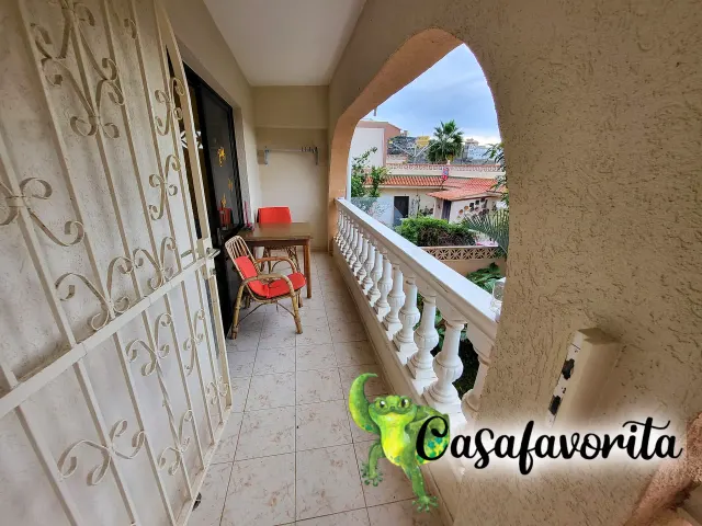 BookNoFees: vakansiehuis in Buen Paso, Tenerife, Spanje – Balkon met tafel, rooi stoele en uitsig oor dakke en palmbome