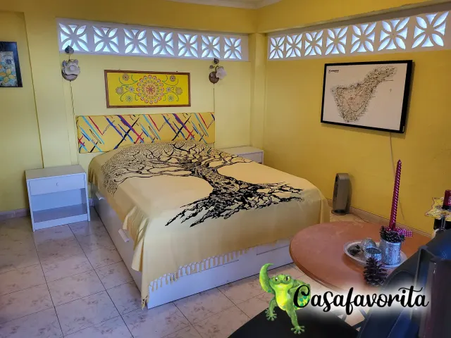 BookNoFees self catering holiday home in Buen Paso, Tenerife, Spain – Bedroom with double bed, tree-patterned bedspread, and decorative concrete block windows