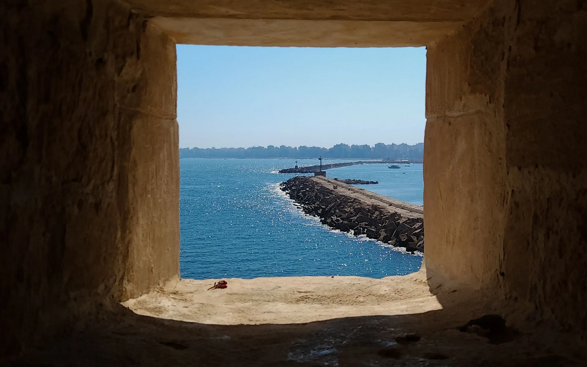 A view of the sea through a historic stone window in Alexandria