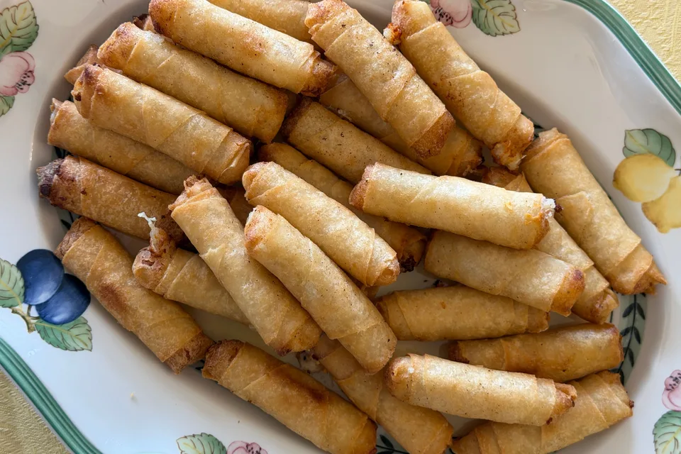 Voorbeeldfoto: Goue gebraaide springrolls op 'n patroonbord
