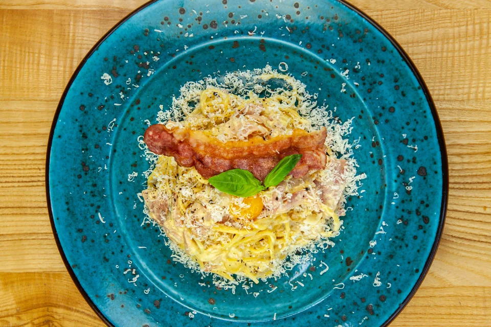 Voorbeeldfoto: Spaghetti carbonara op 'n blou bord