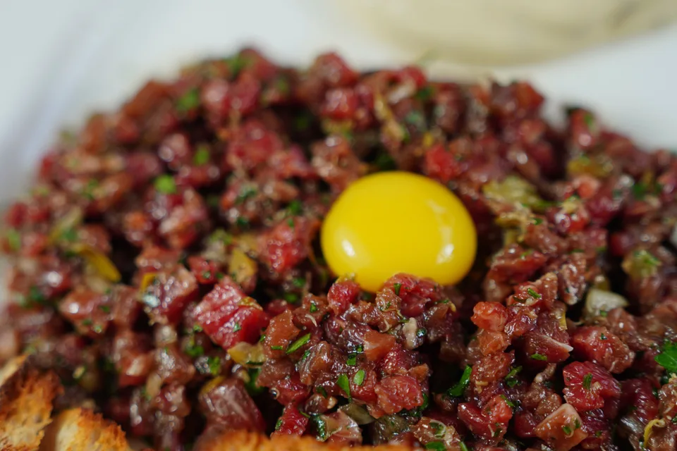 Voorbeeldfoto: Steak tartare met eiergeel bo-op en geroosterde brood bedien